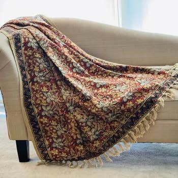 Decorative floral-patterned propulsion  with tassels draped elegantly implicit    a beige sofa, adding a interaction   of elegance and comfortableness  to location  decor