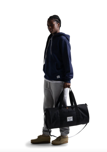 model holding black duffel gym bag