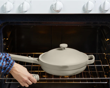 a model pulling the pan out of the oven