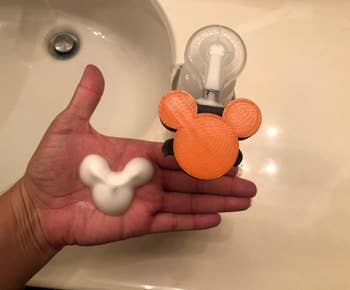 hand using the orange pump to pump out mickey face and ears-shaped foam soap