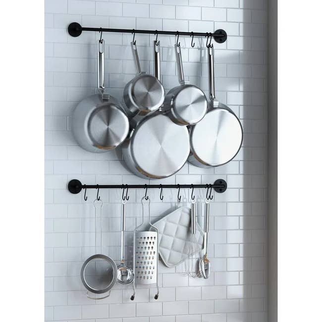 the two pot and pan racks installed on a wall and holding carious pots and utensils