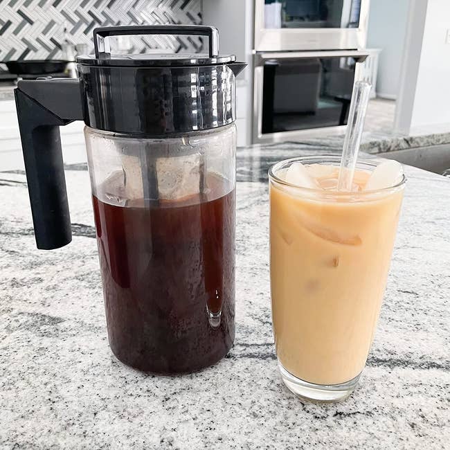 Cold brew coffee pitcher next to an iced coffee drink 