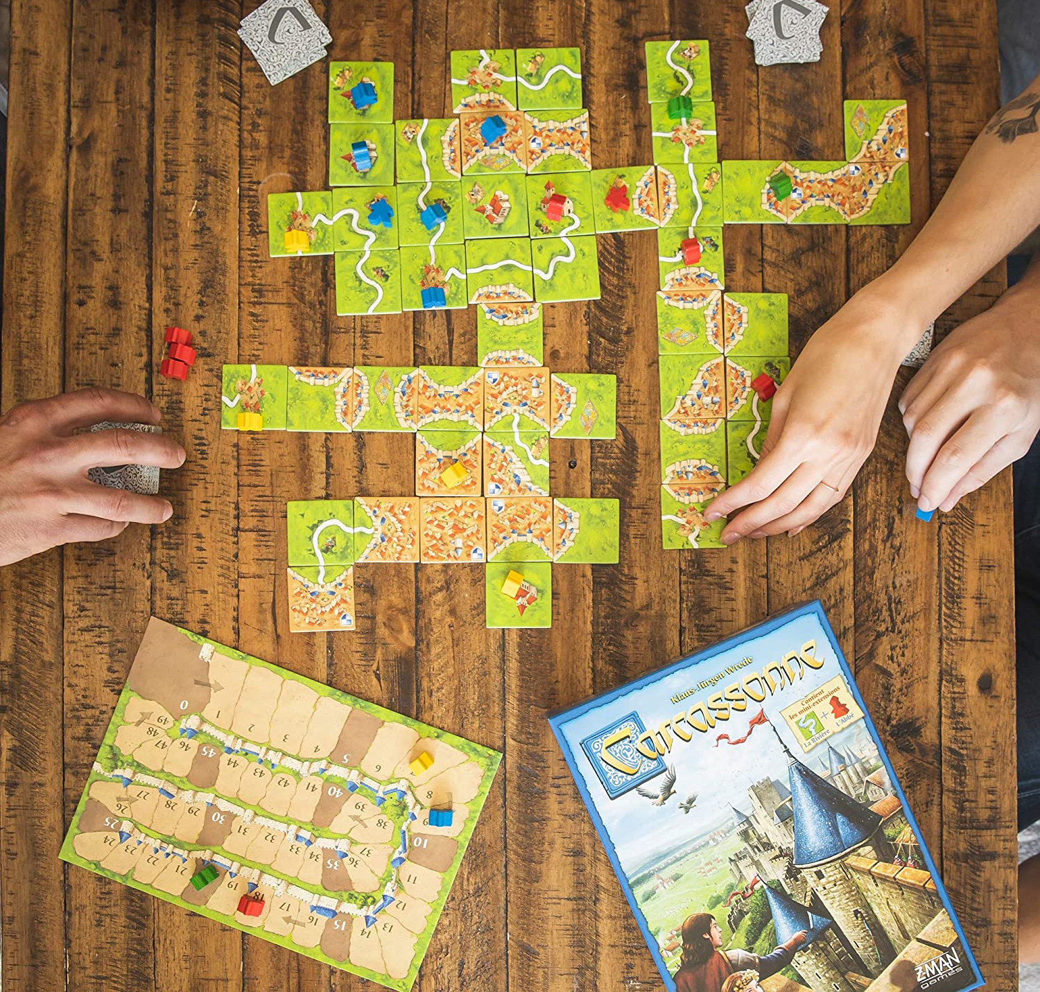 a top-down view of a table set up with Carcassonne tiles and the board game box 