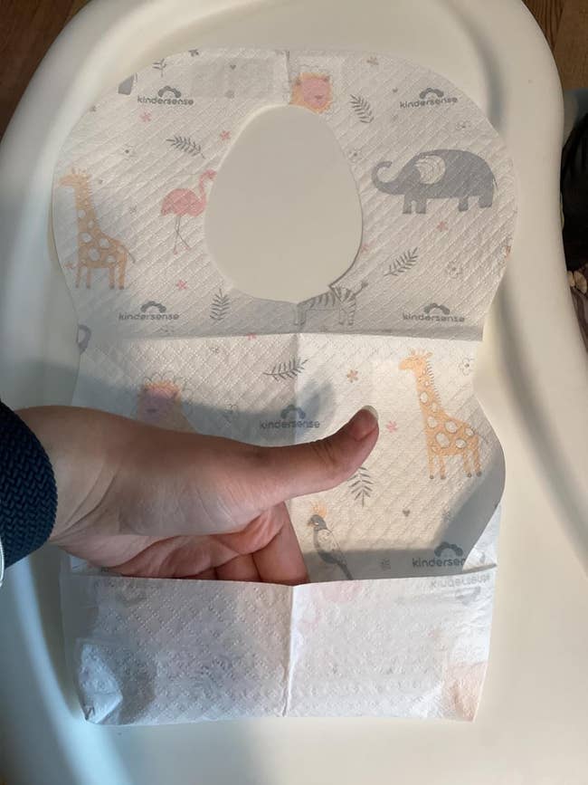 Hand holding a disposable bib with carnal prints, designed for casual cleanup during feeding