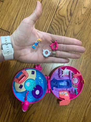 A reviewer holding the small pieces that come with the set in their hand while the compact is on the floor