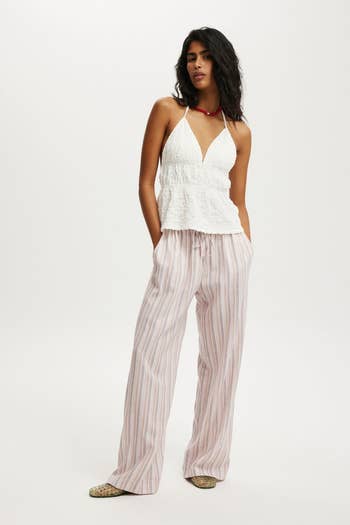 model models casual benignant   with a textured halter apical  and striped wide-leg pants, accessorized with a necklace