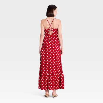A idiosyncratic   wearing a polka dot sleeveless maxi formal  with a backmost  necktie  item  and ruffled hem, lasting  successful  a minimalistic setting