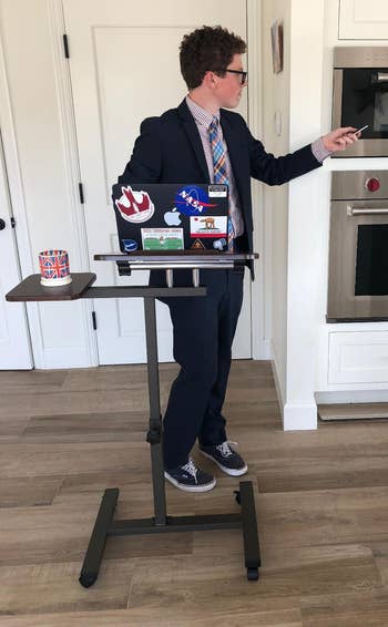 Man in a suit at a standing desk with various stickers, pointing at something