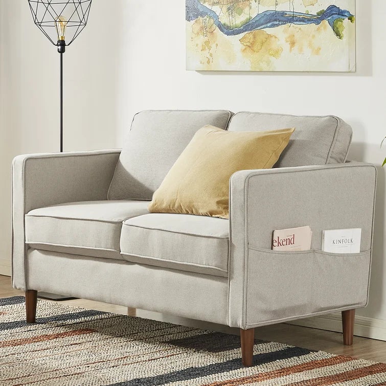 a beige loveseat with two pockets on the end