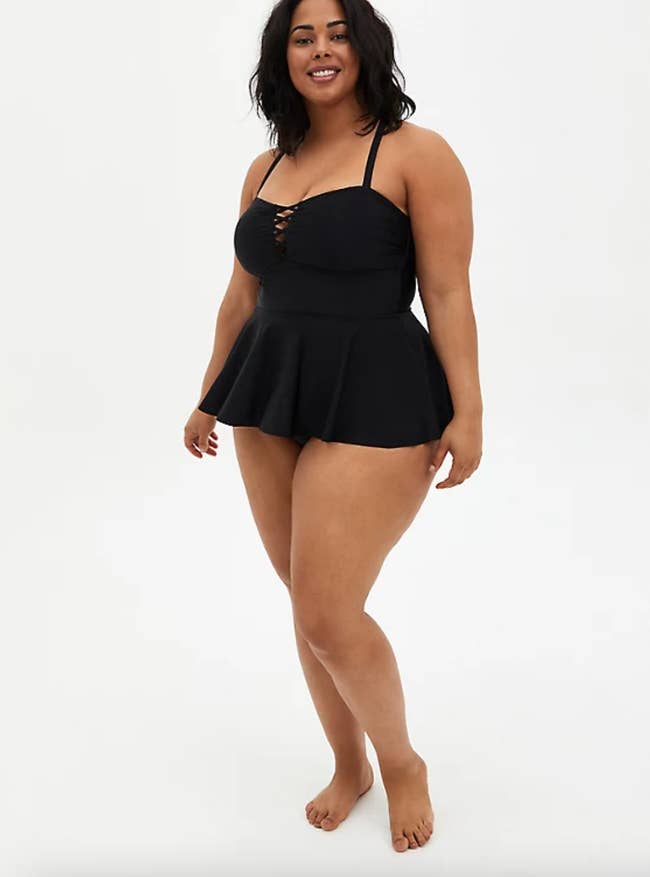 A model in a black strappy peplum skirt swimsuit