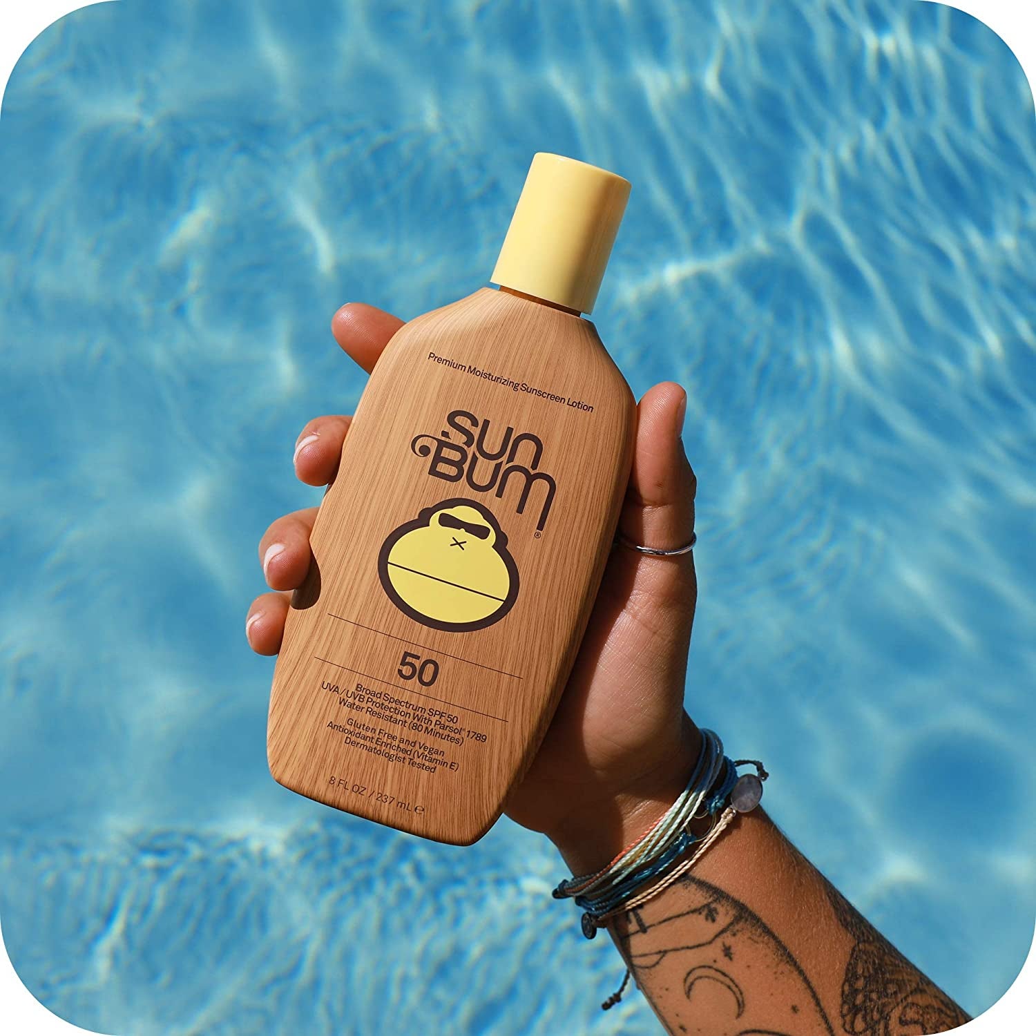 brown bottle of Sun Bum SPF 50 sunscreen in hand