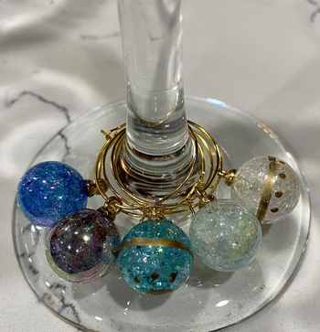 several of the charms wrapped around the stem of a glass