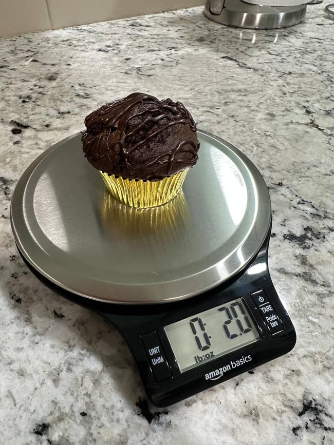 Chocolate cupcake with frosting connected a integer room standard displaying 2.0 ounces, resting connected a marble countertop