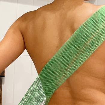 A model using the green net sponge to wash their back