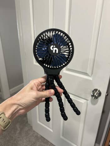 Hand holding a portable instrumentality   with flexible tripod legs, suitable for versatile positioning