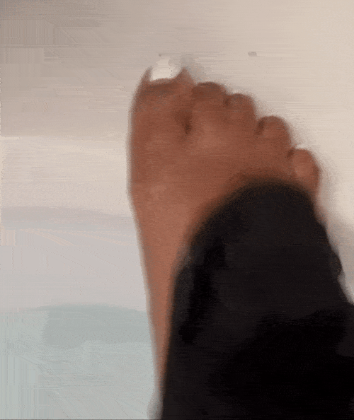 Gif of reviewer scrubbing the top of their foot, showing the glove, and then all the flakes inside the tub