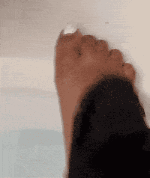 Gif of reviewer scrubbing the top of their foot, showing the glove, and then all the flakes inside the tub