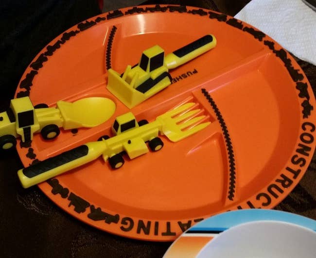 reviewer photo of an orange plate with spots for utensils shaped like construction vehicles