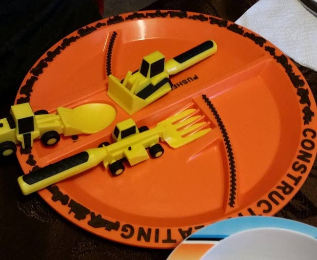 reviewer photo of an orange plate with spots for utensils shaped like construction vehicles