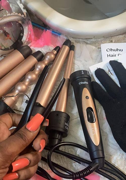 reviewer displaying curling wand set and included items