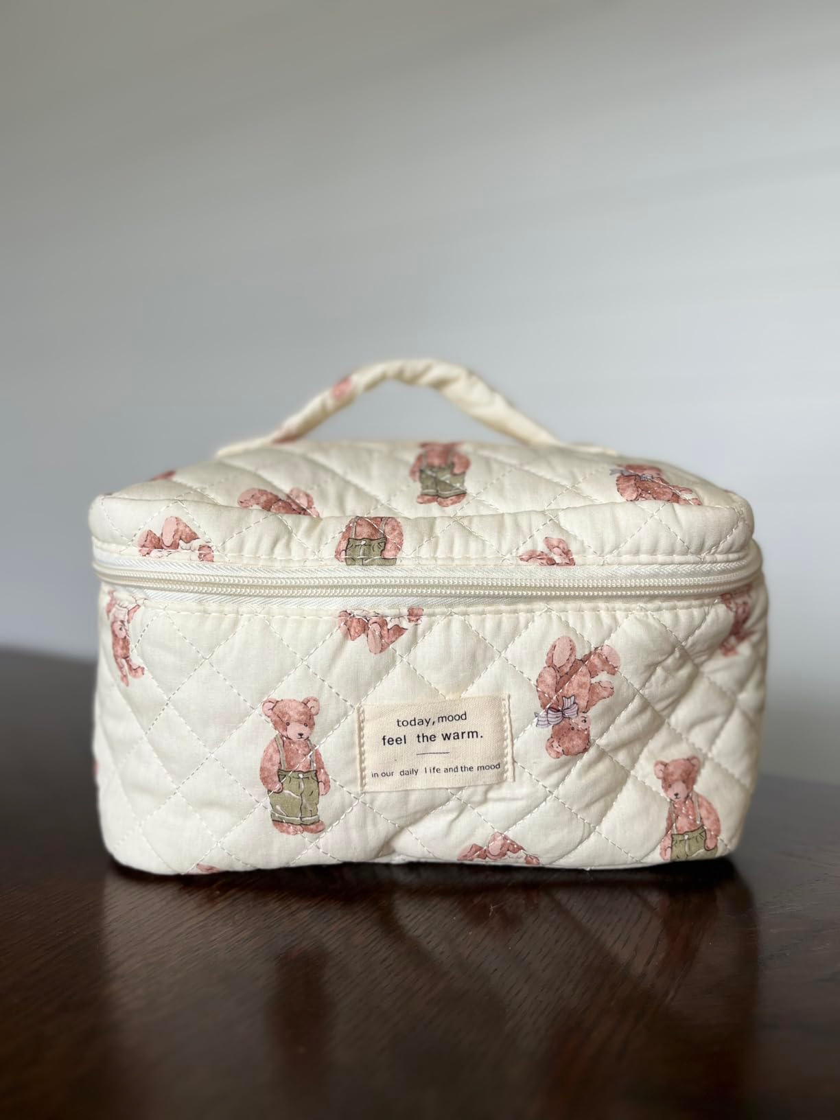 Quilted cosmetic container  with carnivore  prints and a handle, displaying the operation   