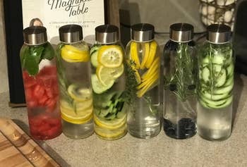a reviewer's six water bottles filled up with different fruits