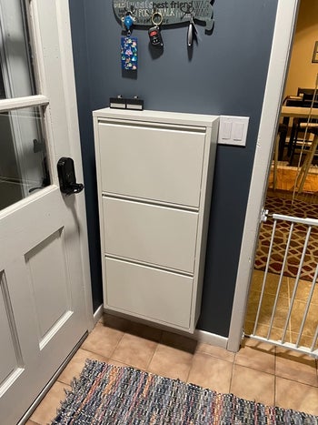 reviewer photo of white shoe cabinet closed, mounted near entryway