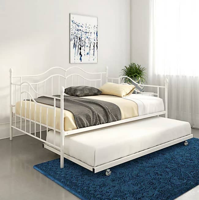 lifestyle image of white metal bed with trundle rolled out