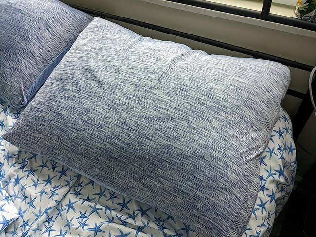 the blue-gray cooling pillowcases on pillows on a reviewer's bed