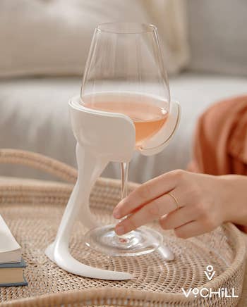 model grabbing the stem of a stemmed wineglass that's sitting in a wine chiller