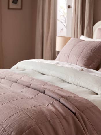 A neatly-made bed with plush bedding and a textured comforter, suggesting a cozy shopping theme for home decor