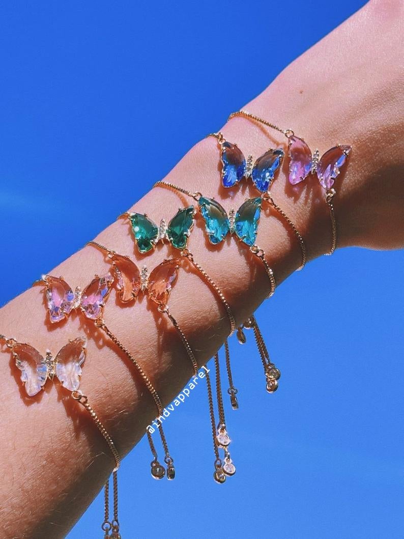 model wearing the crystal butterfly on a chain bracelets stacked in a rainbow of colors