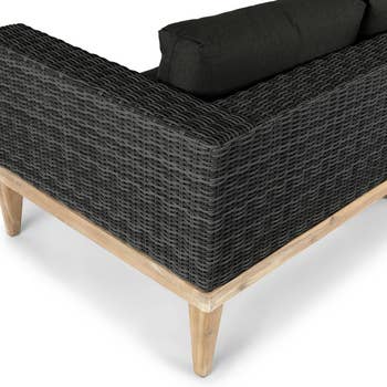 Outdoor wicker-style sofa with woody  legs and acheronian  cushions, showcasing modern   patio furnishings  design
