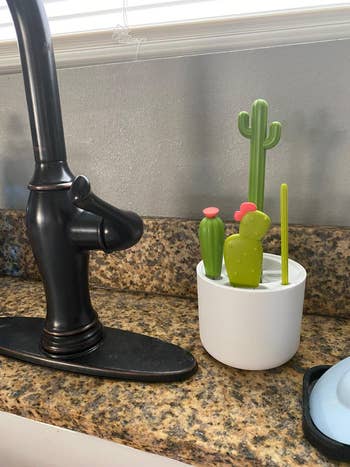white pot with four brushes with cactus shaped handles sticking out