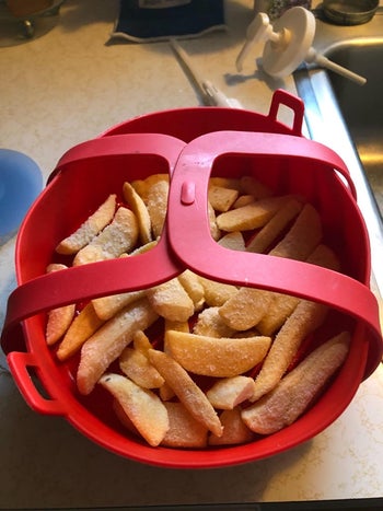 Frozen fries sitting in the red silicone basket with handles
