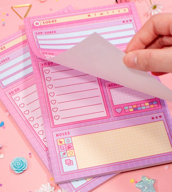 a hand turning the page on the pink retro style notepad