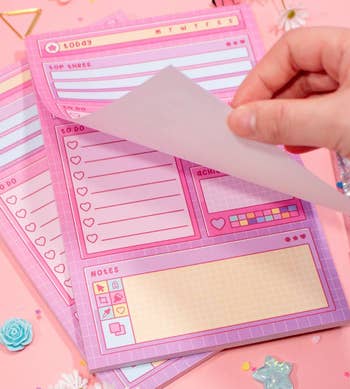 a hand turning the page on the pink retro style notepad