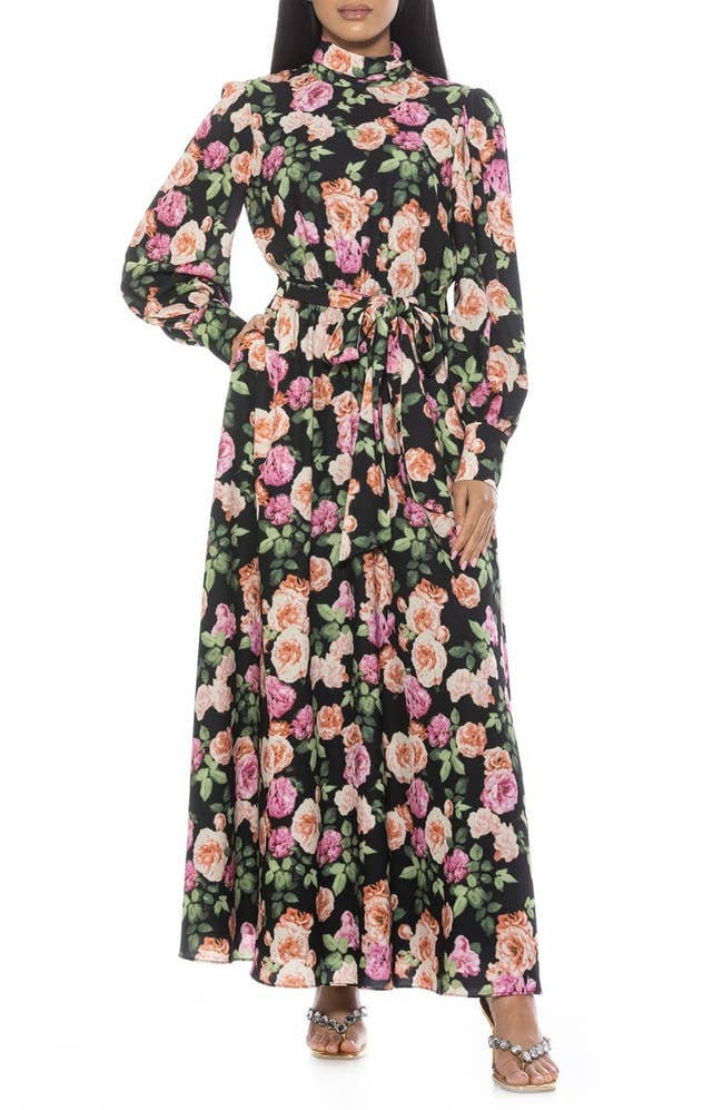 Model wearing a long-sleeved floral maxi dress with a high neckline and tie waist
