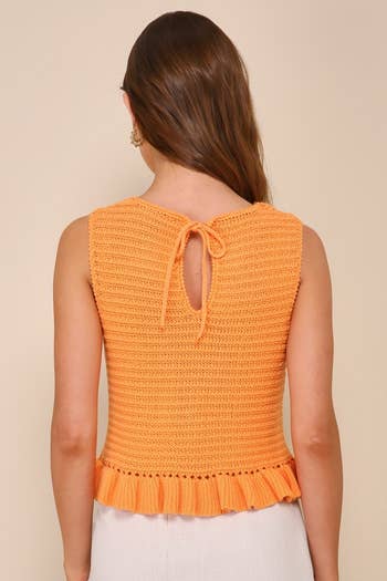 Person showcasing a knit orange top with tie detail at the back, for a shopping article
