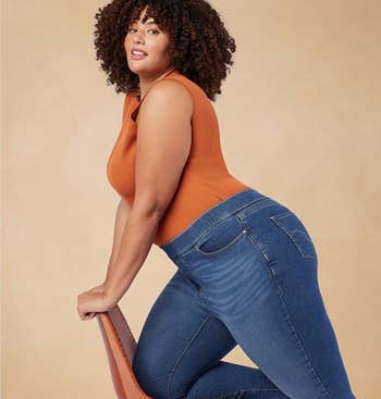 Person successful a sleeveless apical and jeans poses stylishly connected a chair, illustrating fashionable, comfy covering options