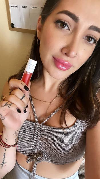 reviewer holding the lip oil while also wearing it