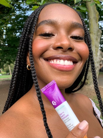 model smiling while holding the berry balm dotcom