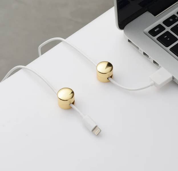 two small round gold cable clips on desktop holding charger cords