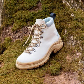 White hiking footwear  with rugged sole connected  mossy surface, showcasing durability and outdoor style