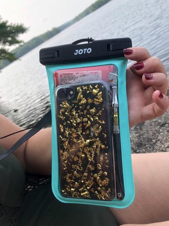reviewer holding the case with their phone in it next to the water