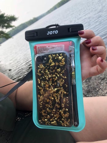 hotel customer holding the case with their phone in it beside the water