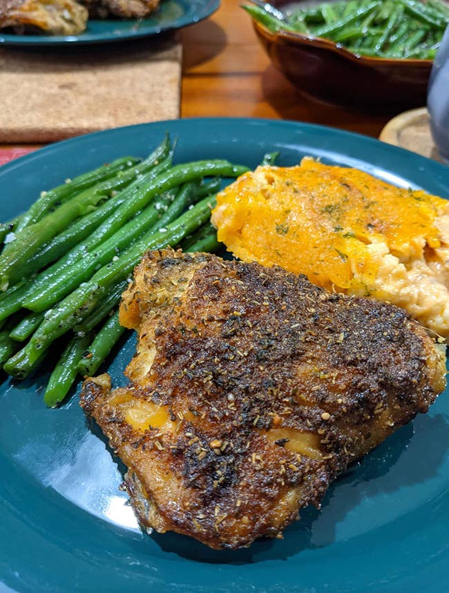 The spices on a steak and mashed potatoes and green beans 