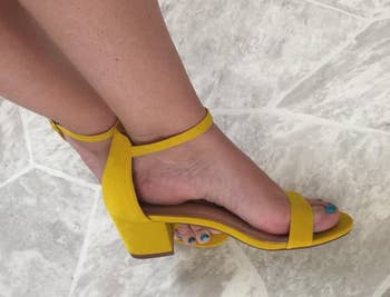Person wearing yellow block-heel sandals with toe straps