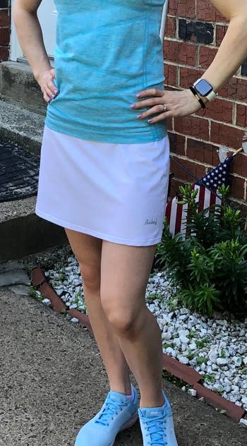 reviewer wearing skort in white with blue top and sneakers