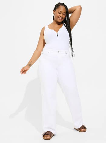 Model in white tank top and high-waisted white jeans